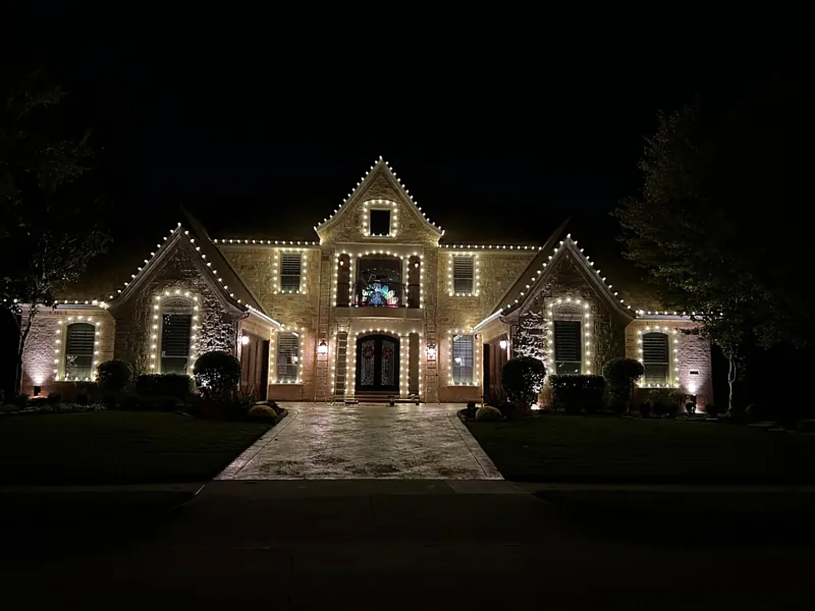 Christmas lights glowing along a roofline at night